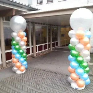 Twee ballonzuilen met zilveren toppen voor de ingang van een gebouw. ​