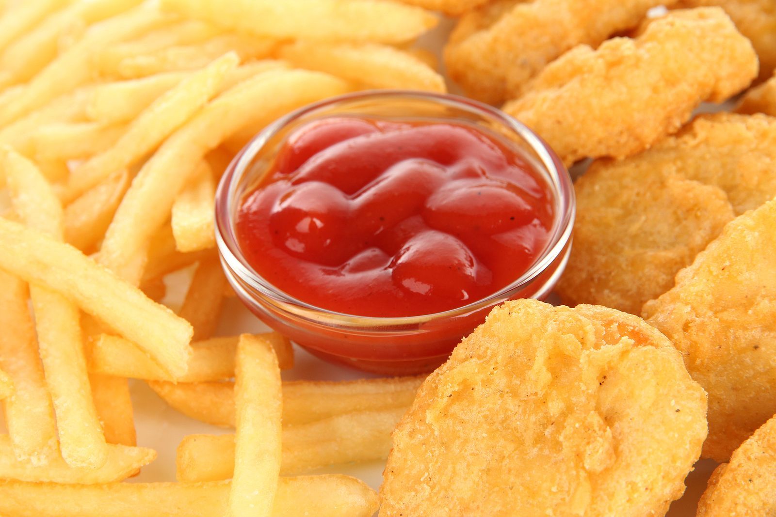 Friet, kipnuggets en ketchup in een klein glazen kommetje.