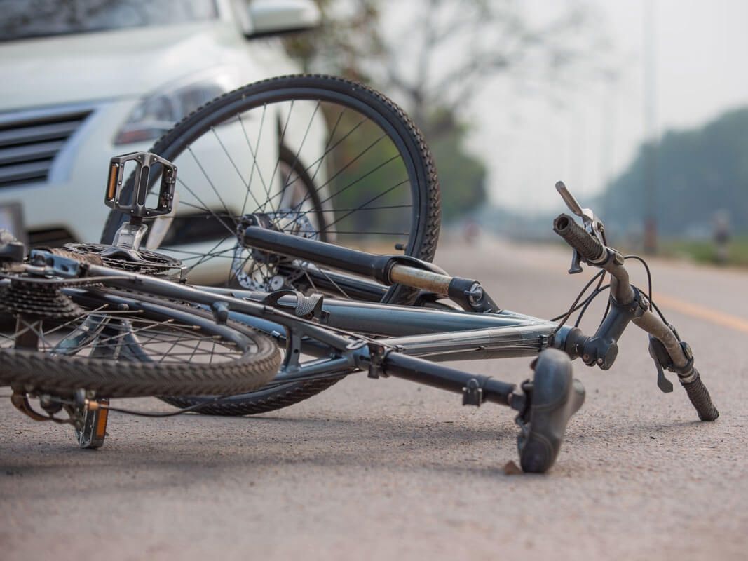 Overturned black bicycle lying on a sidewalk near a curb because of vehicle collision