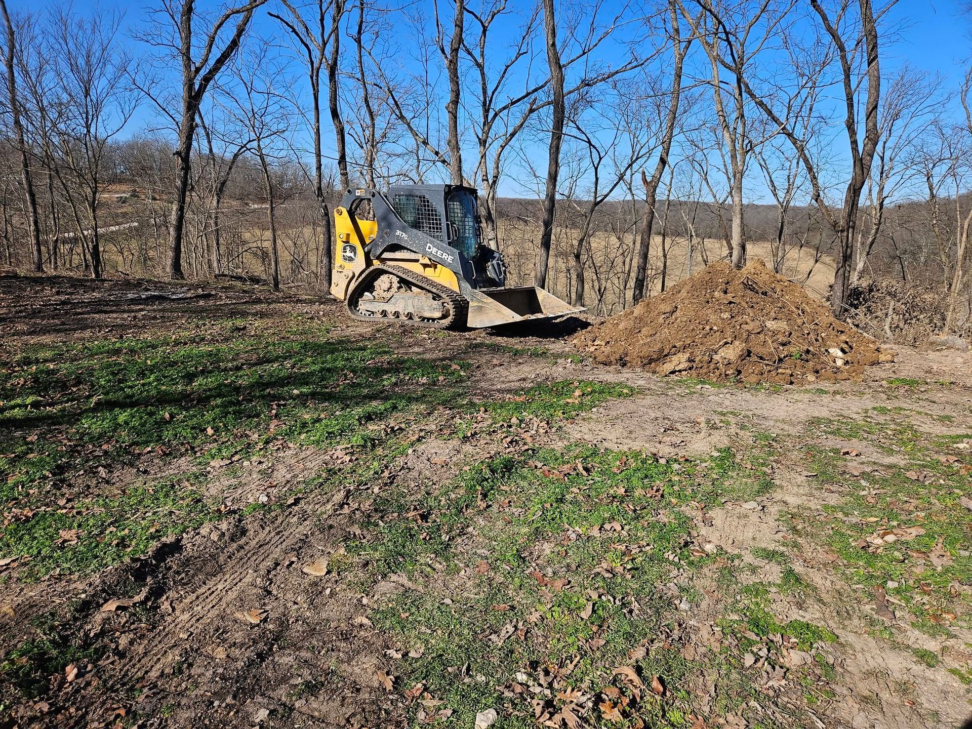 Skid steer loader leveling soil at a construction site, working on rough terrain