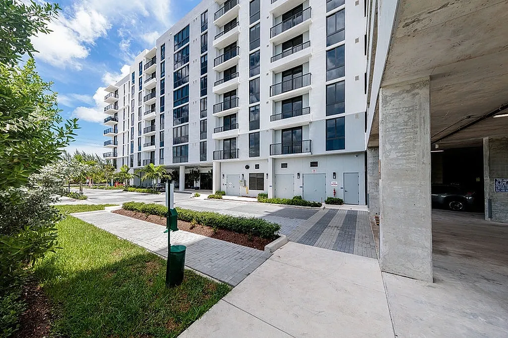 Tides at River Rapids apartments building exterior with modern architecture, lush greenery, and spacious pathway.