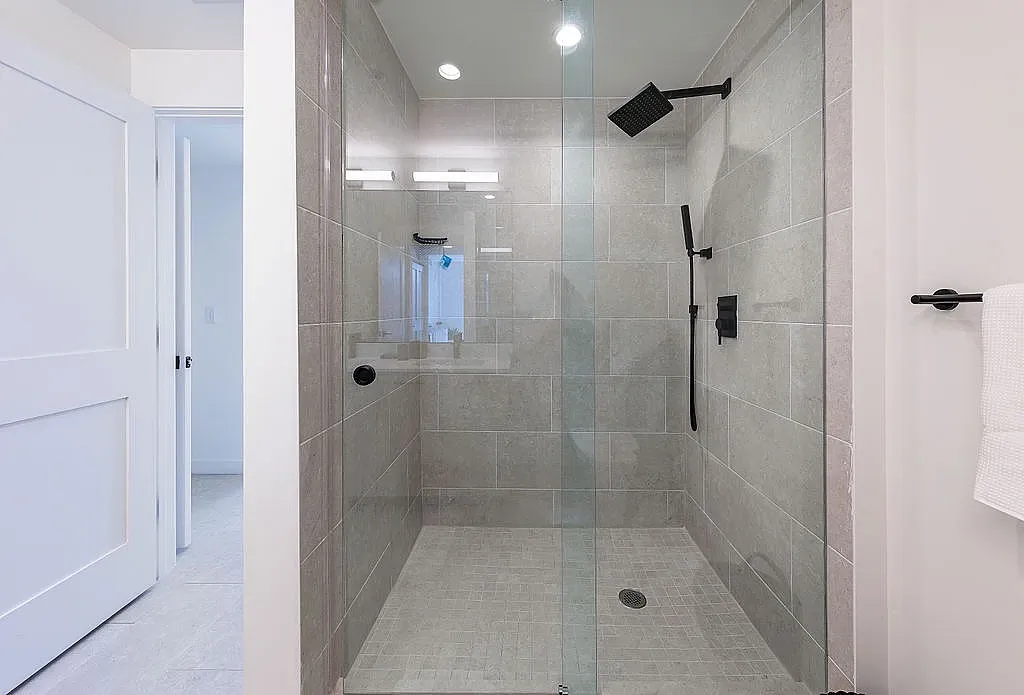 Luxurious spa-inspired shower with sleek glass doors and elegant fixtures in a serene tile setting.