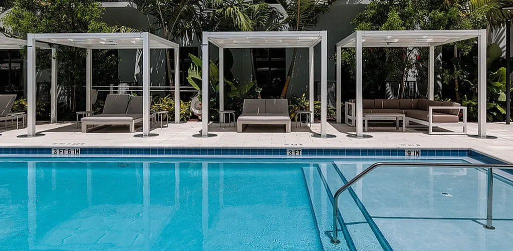 Luxurious outdoor pool area with stylish cabanas and lush greenery, perfect for relaxation and leisure.
