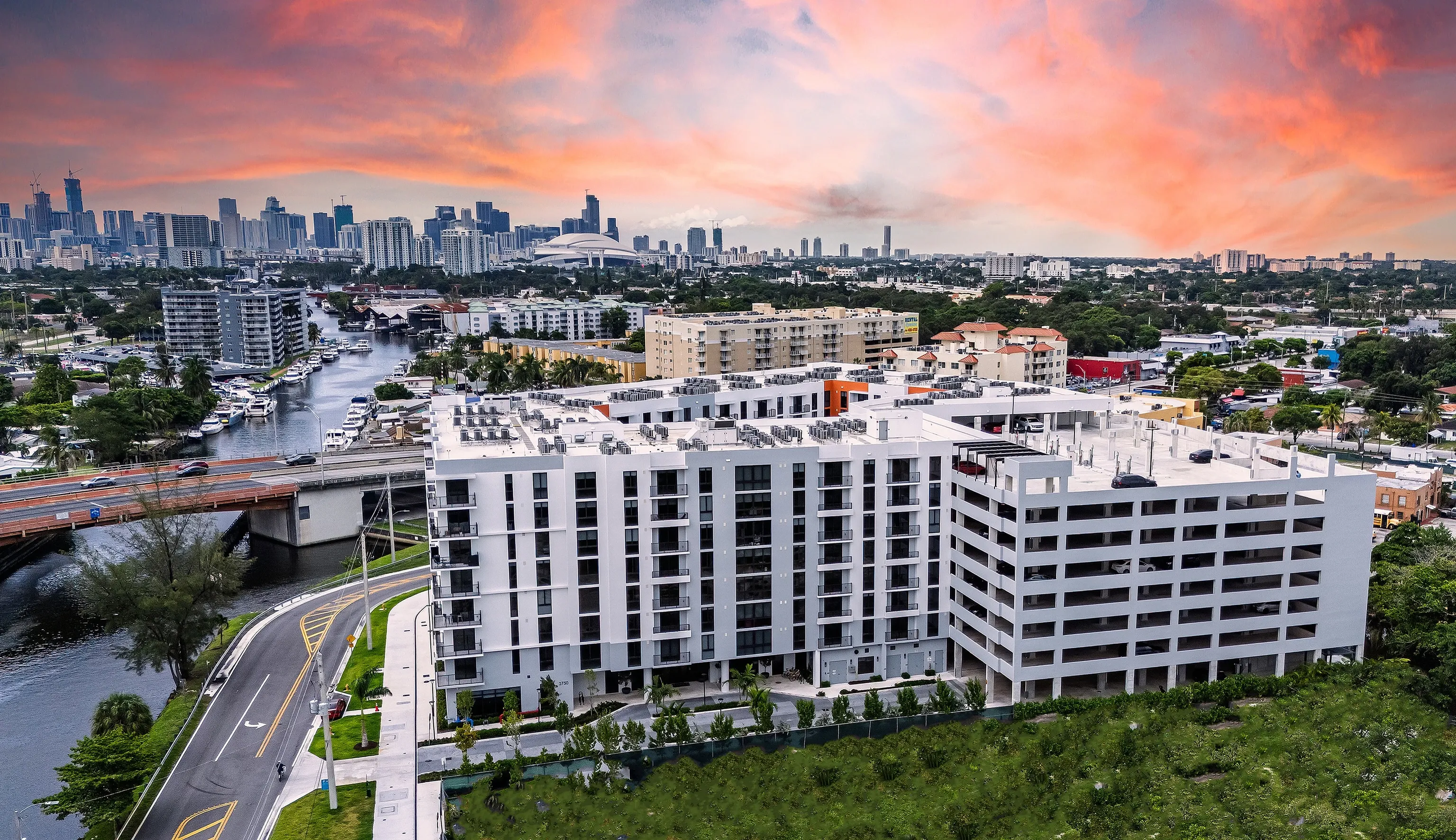 Aerial view of Tides at River Rapids has modern architecture, a centralized location, and vibrant cityscape under a stunning sunset sky views.