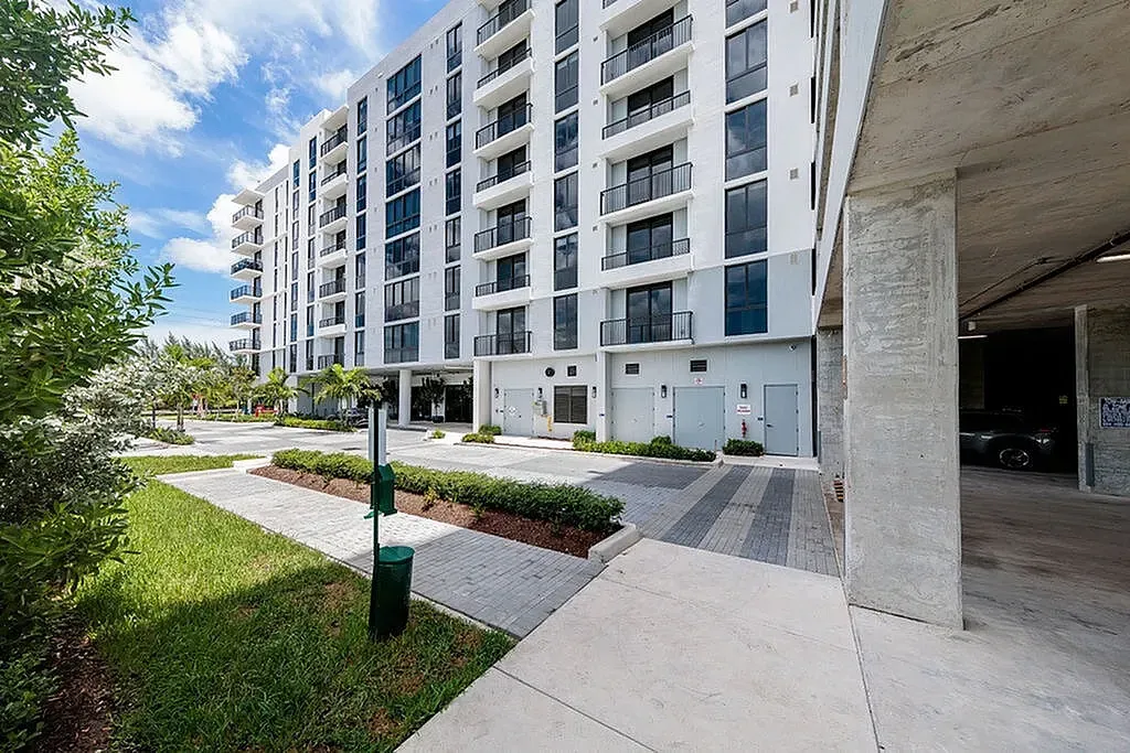 Tides at River Rapids apartments building exterior with modern architecture, lush greenery, and spacious pathway.