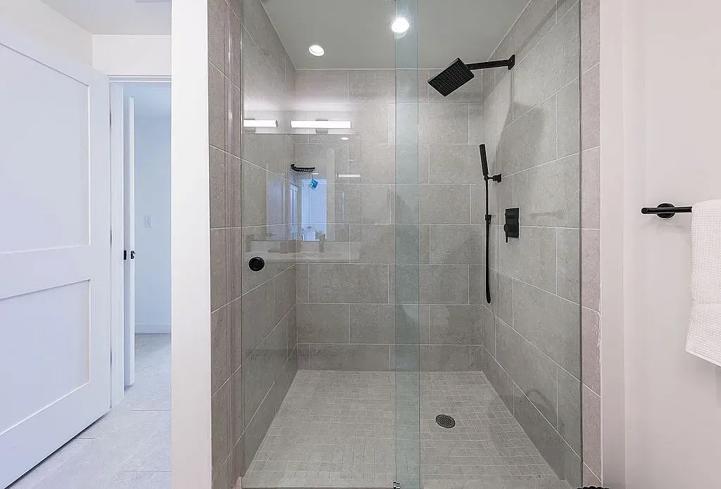 Luxurious spa-inspired shower with sleek glass doors and elegant fixtures in a serene tile setting.