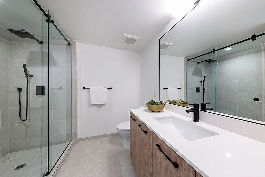 Modern bathroom featuring a sleek glass shower, elegant vanity with ample counter space, and contemporary fixtures.
