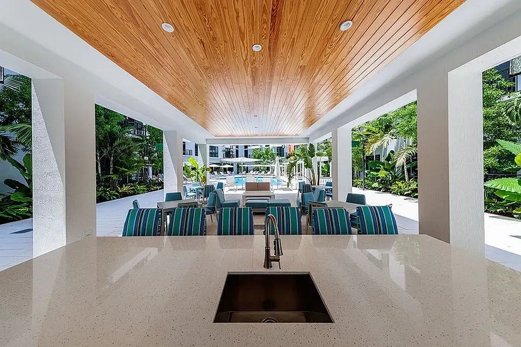 Luxurious outdoor lounge area with elegant wooden ceiling, vibrant seating, and lush garden views.