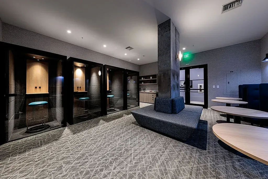 Modern communal area featuring cozy phone booths, stylish seating, and elegant decor, ideal for productive meetings and conducting business.