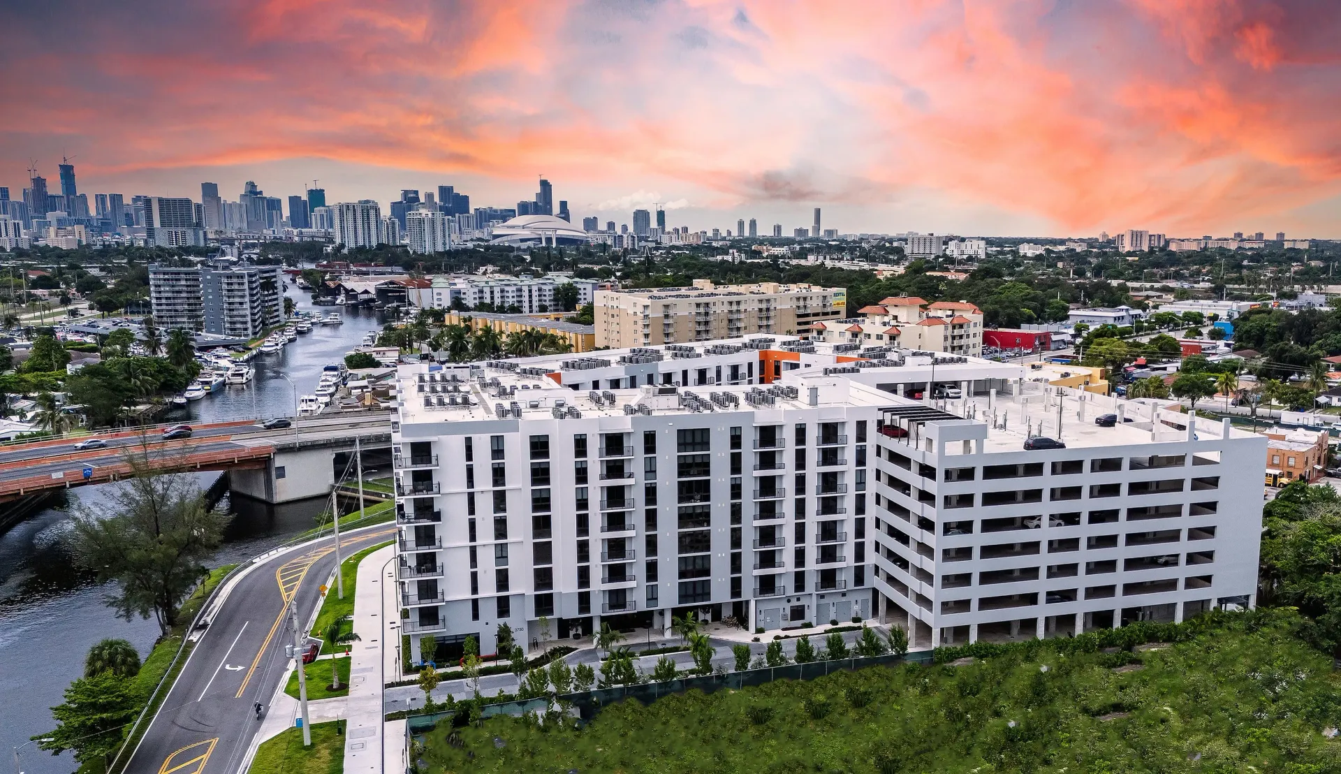 Aerial view of Tides at River Rapids has modern architecture, a centralized location, and vibrant cityscape under a stunning sunset sky views.