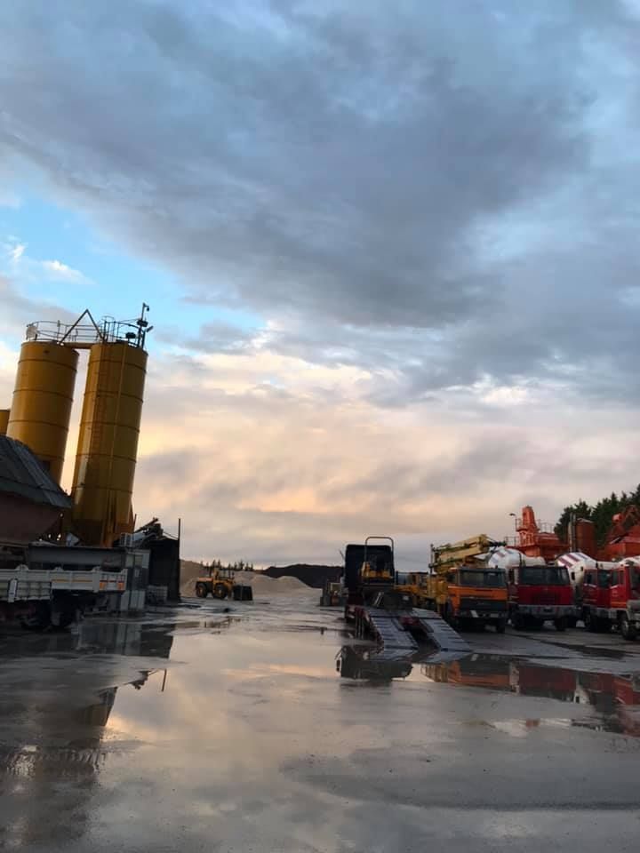 Molti camion sono parcheggiati in un parcheggio con un cielo nuvoloso sullo sfondo