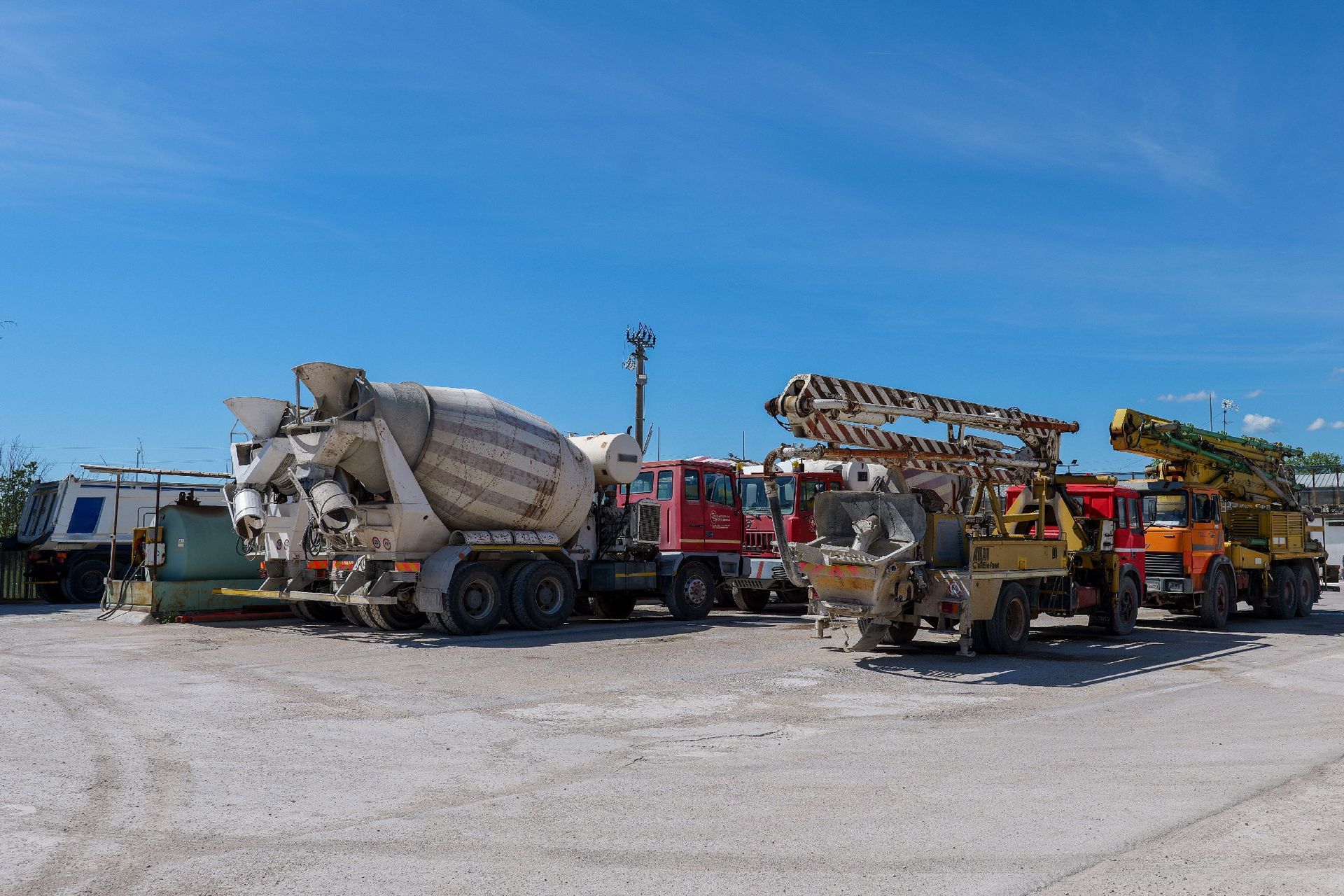 Attrezzature edili parcheggiate su un piazzale ghiaioso sotto un cielo azzurro Centro Beton Potenza