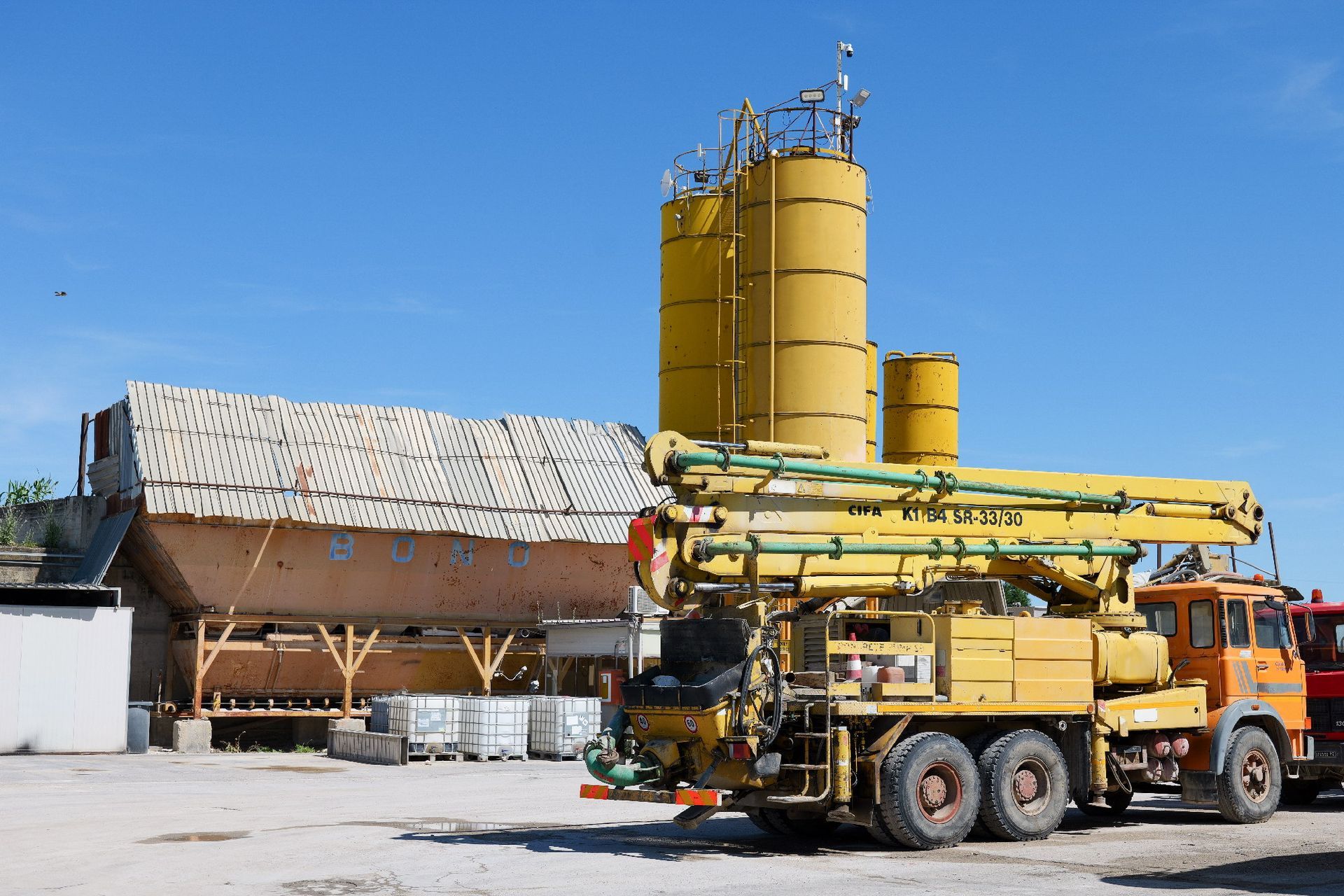 Due betoniere con tamburi rossi e bianchi parcheggiate in un cantiere sotto un cielo azzurro Centro Beton Potenza