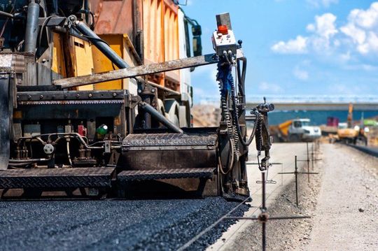 Una macchina sta stendendo l'asfalto su una strada in costruzione.
