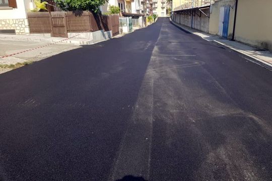 Una strada asfaltata nera con una recinzione sullo sfondo