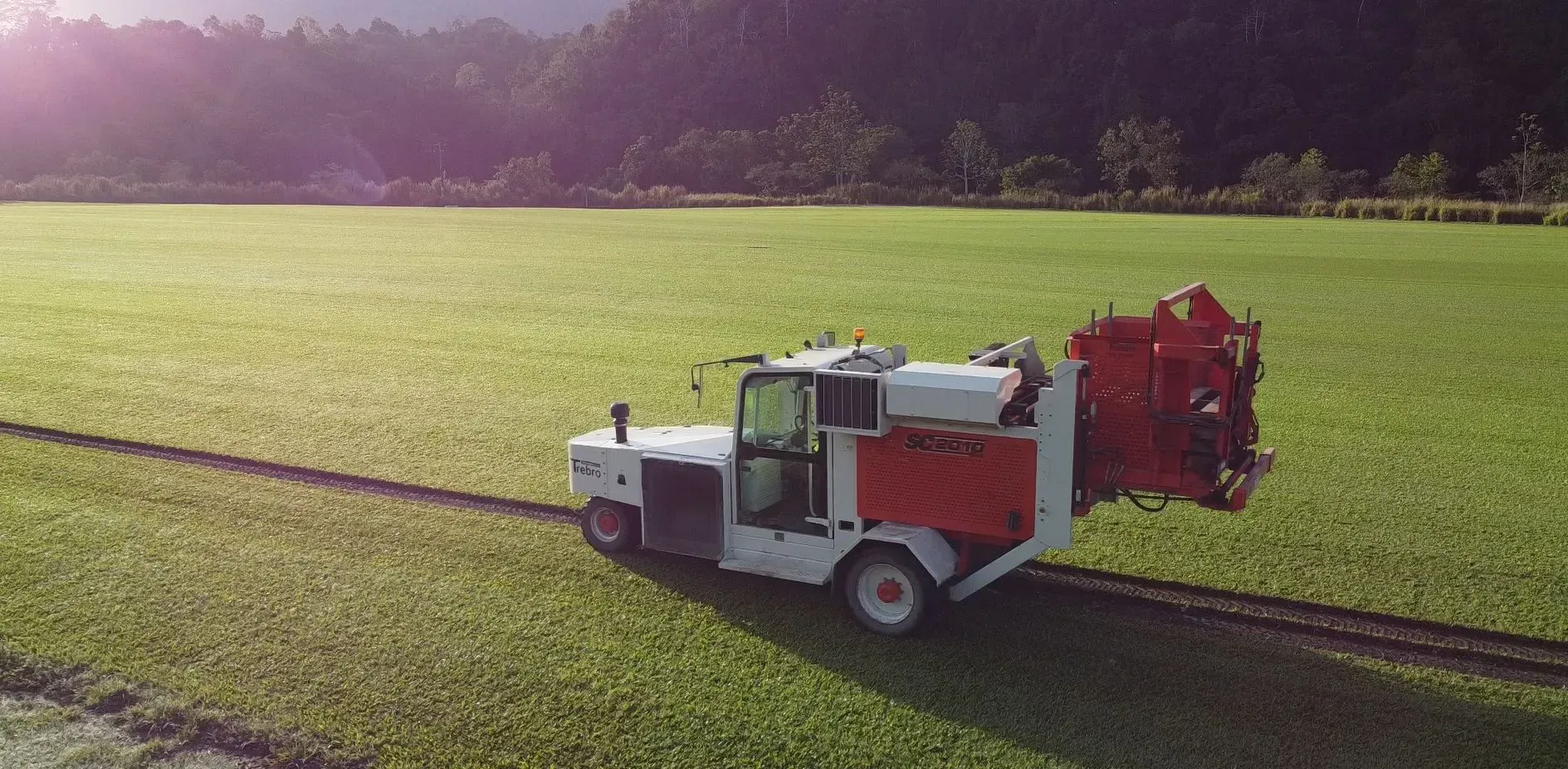 White Agricultural Truck Spraying a Green Field at Sunset — Tropical Lawns in Mulgrave, QLD