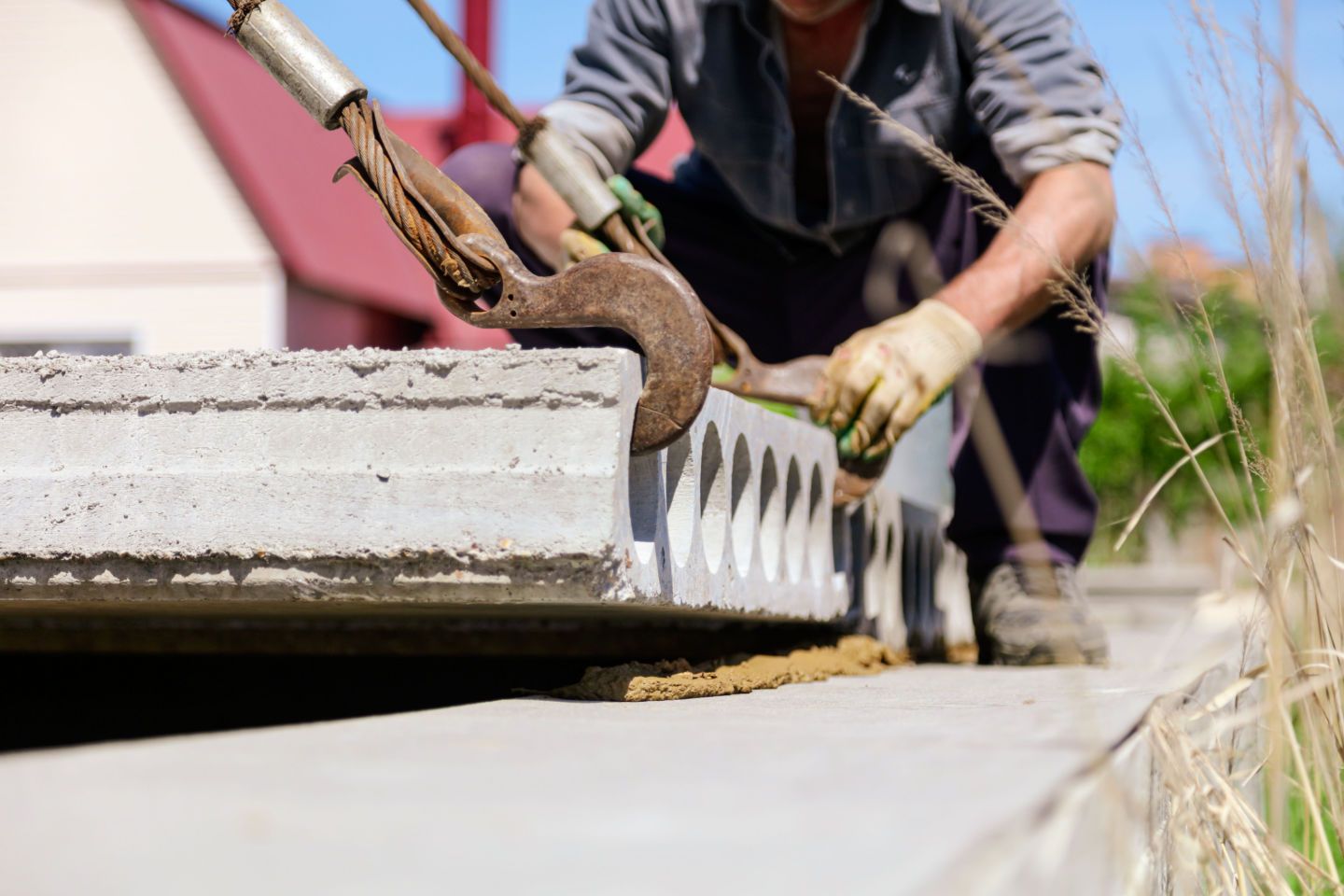 Worker smoothing wet concrete curb with a trowel along a roadside