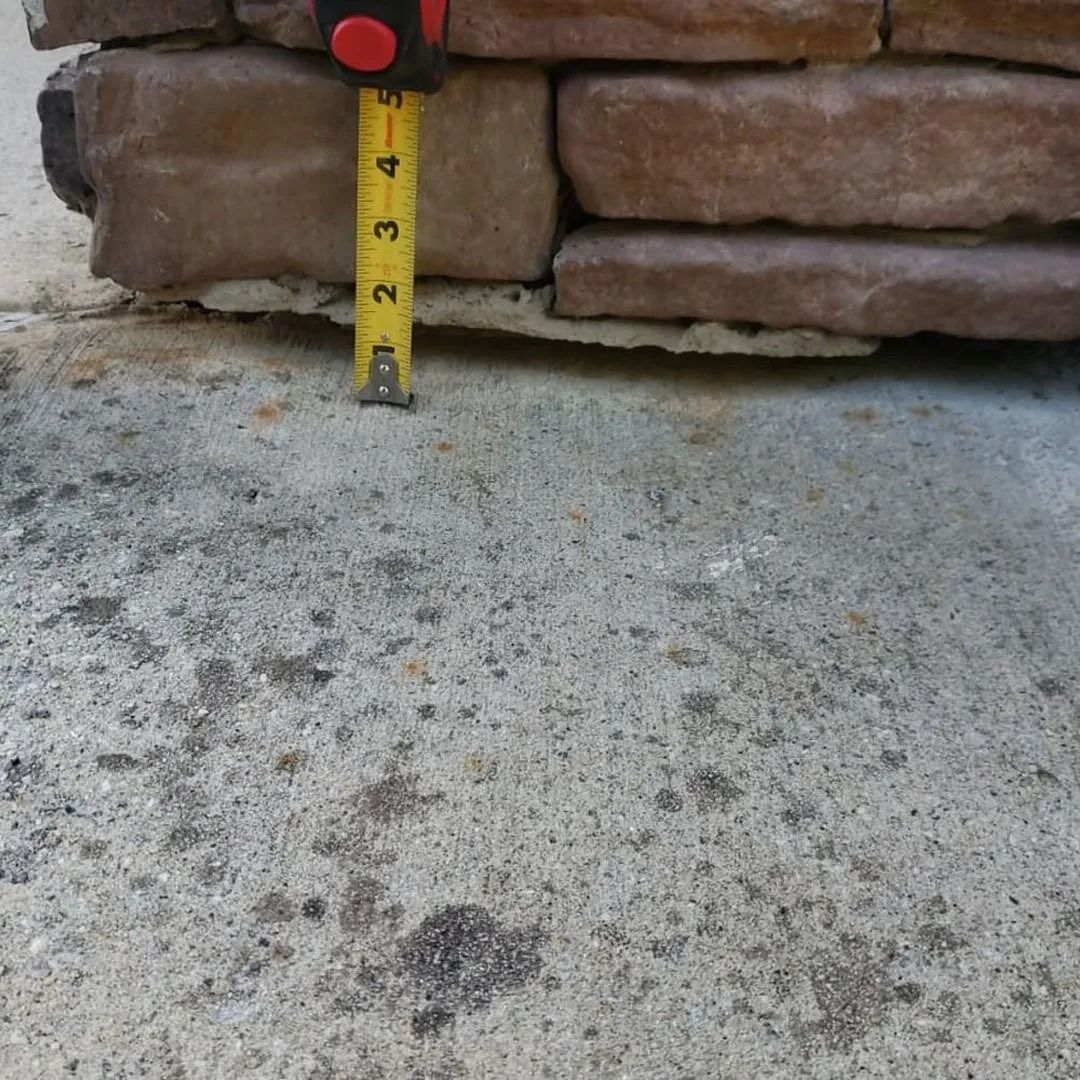 Tape measure against a stone wall above a concrete surface