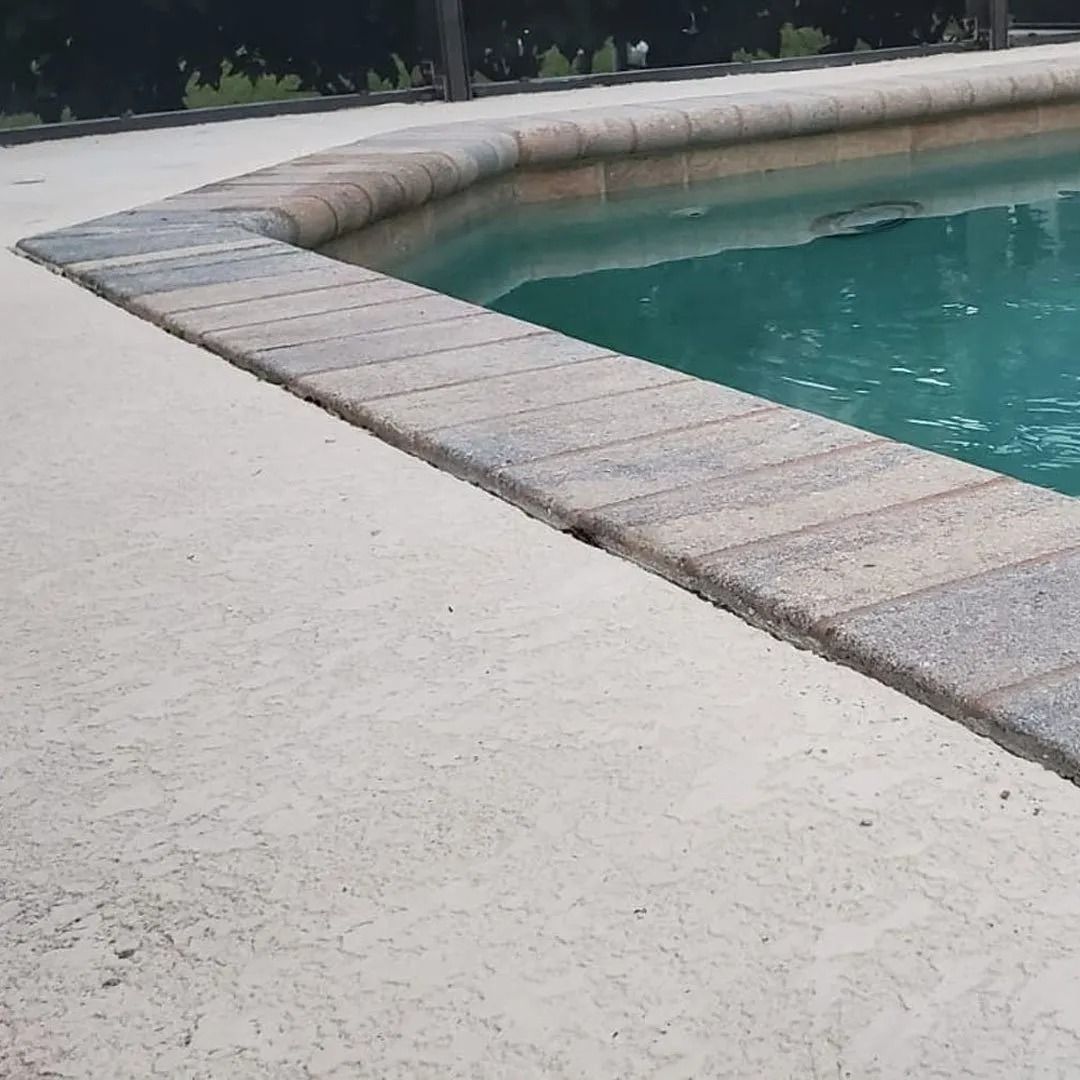 Curved swimming pool edge with light stone coping beside turquoise water