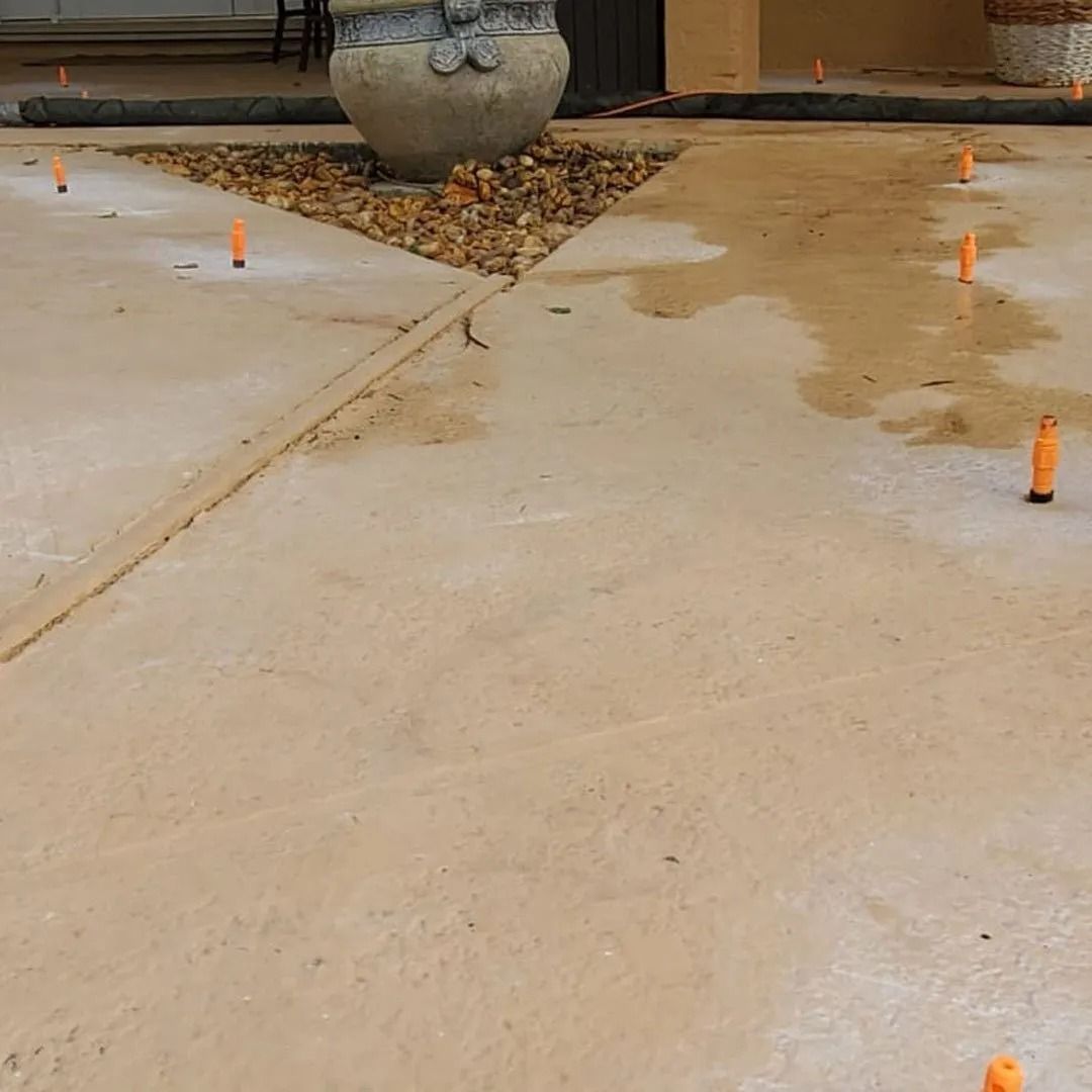 Concrete walkway with small orange cones and a potted planter at the top center.