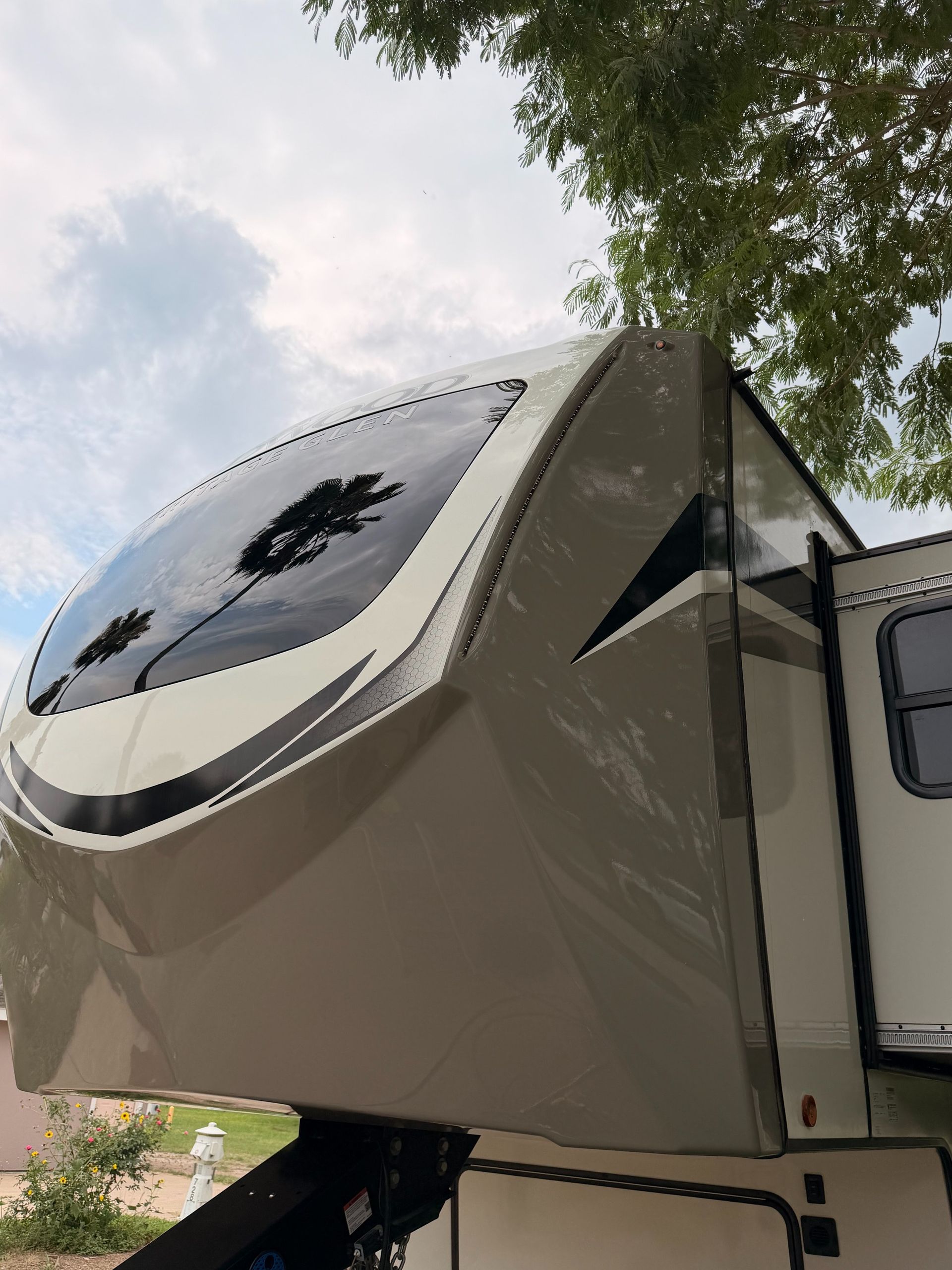 Fold-out camper side panel with a circular skylight, extended outdoors beside a tree and blue sky.