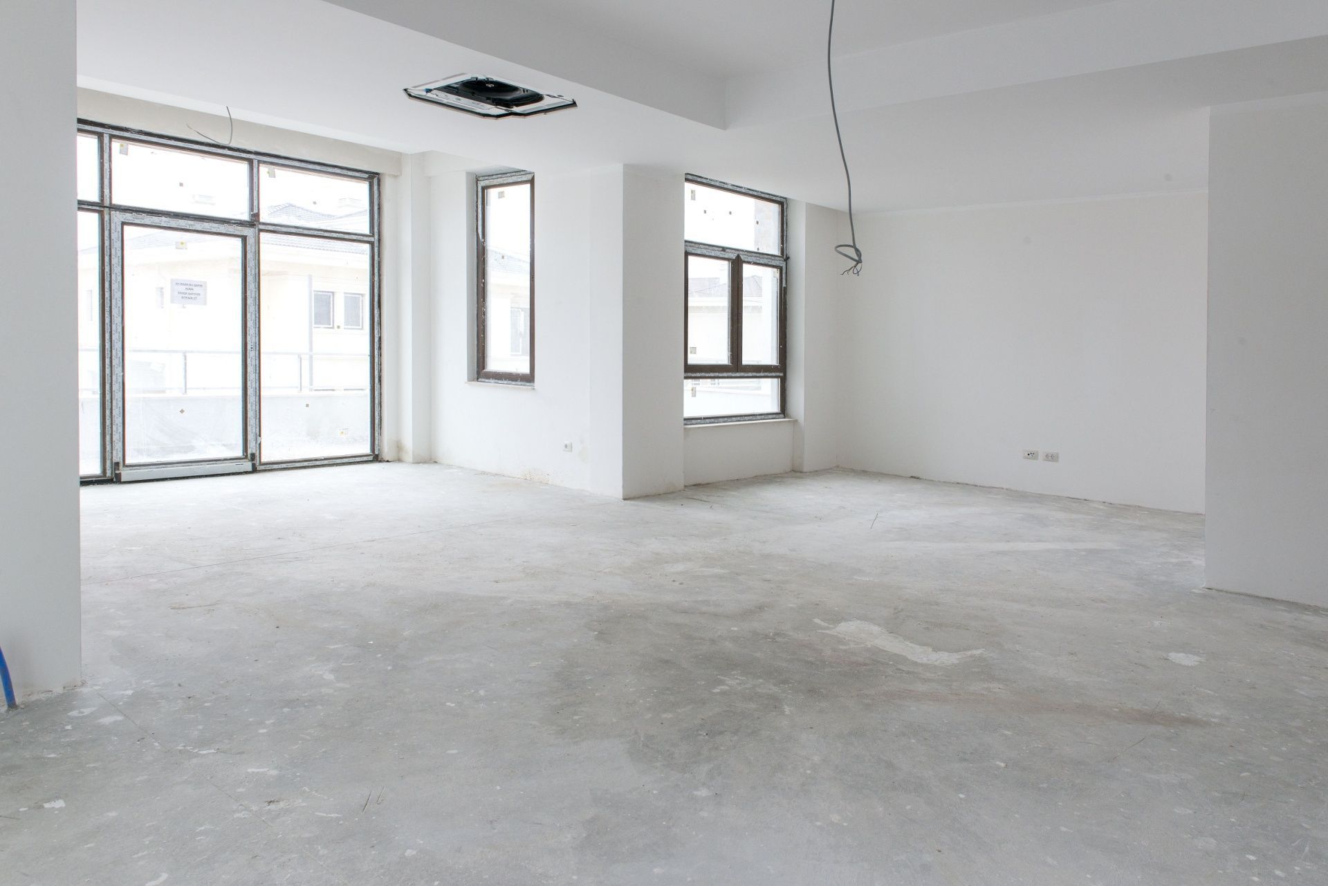 Empty white unfurnished room with large windows and concrete floor