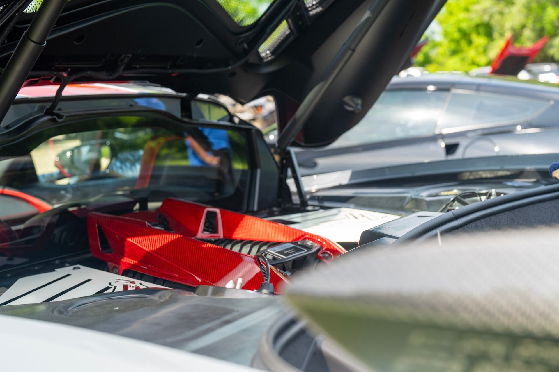 Close-up of a red high-performance engine inside a vehicle with its trunk lid open at a car show.