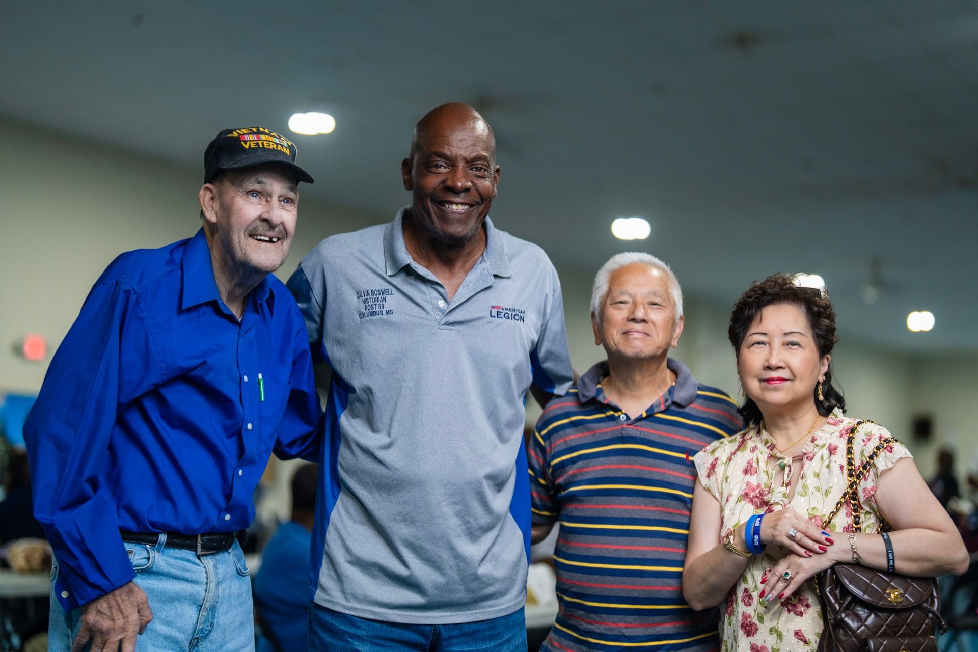 Four people stand together smiling in a brightly lit room, posing for a group photograph.