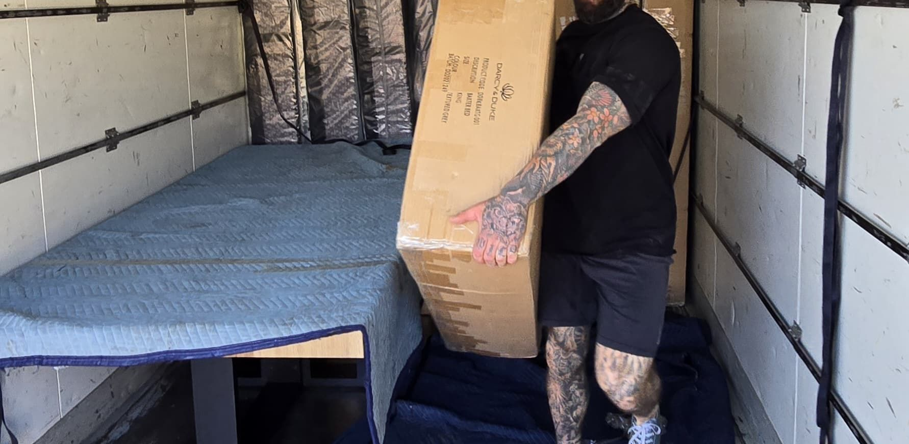 Removalist carrying box of freight from removalist truck.