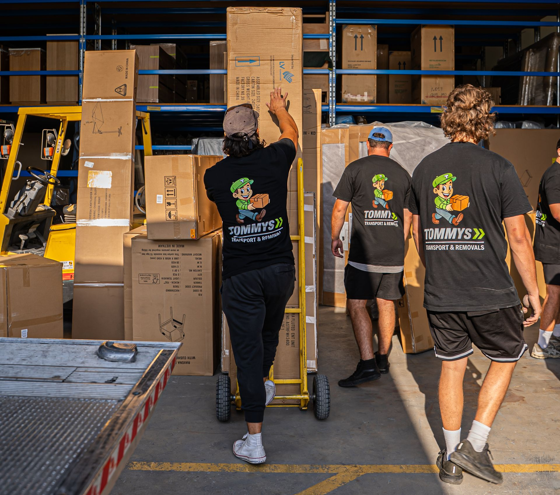 Tommy's transport and removals team unloading moving boxes from the removalist truck using a hand trolley.