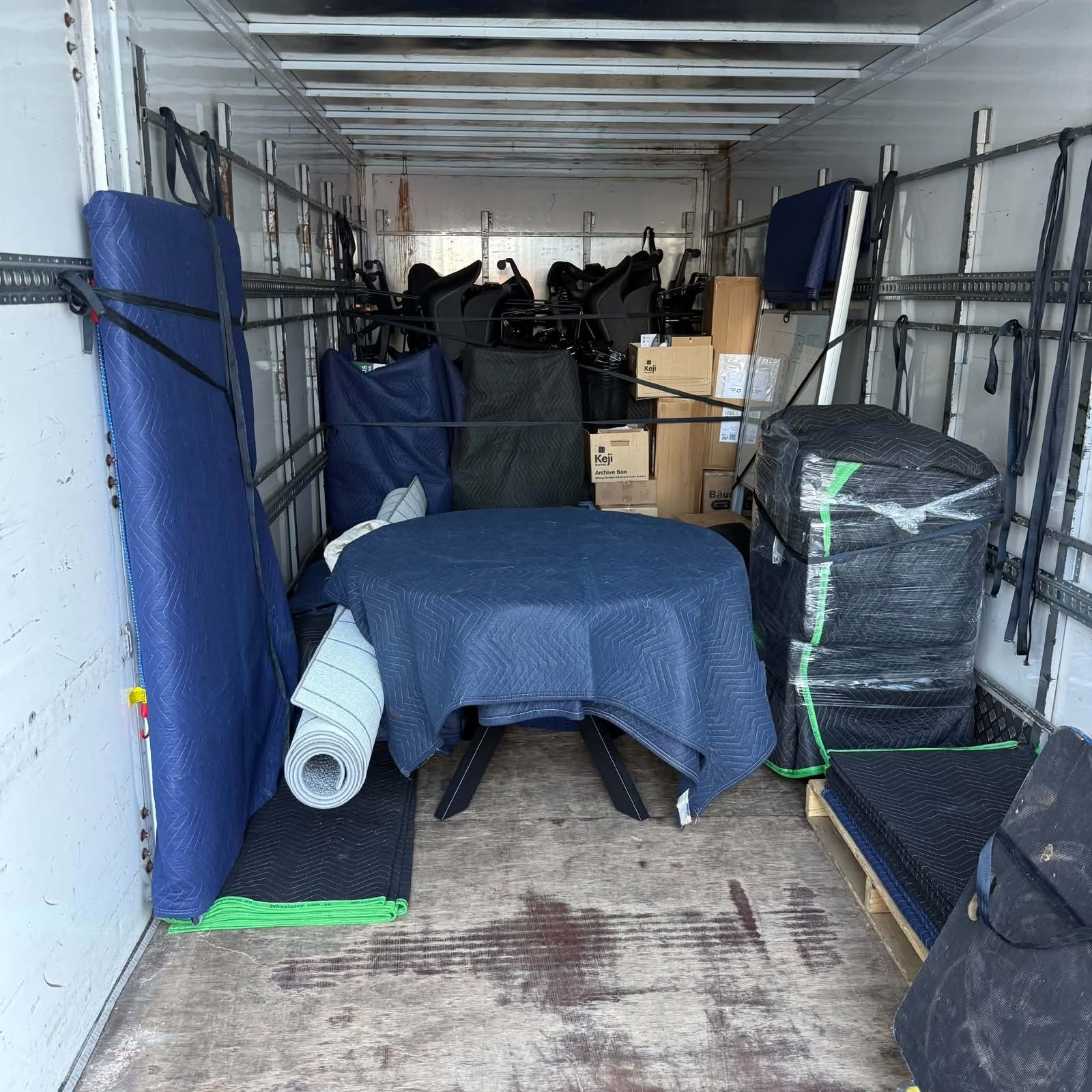 Packed moving truck with stacked furniture, boxes, and covered items inside.
