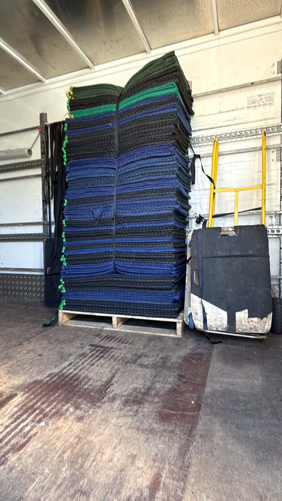Stacked blue and black blankets on a pallet in a truck or warehouse loading area