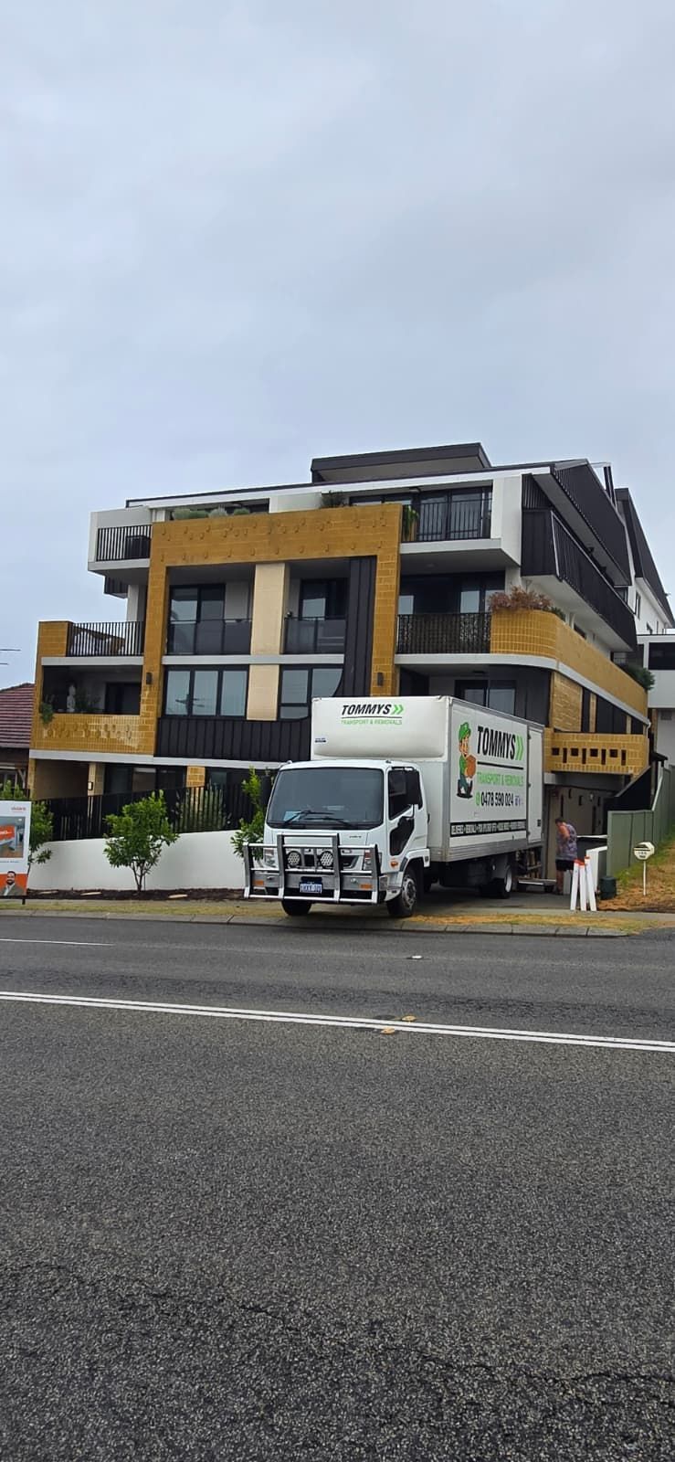 White truck parked in front of a yellow-and-gray commercial building on an overcast street