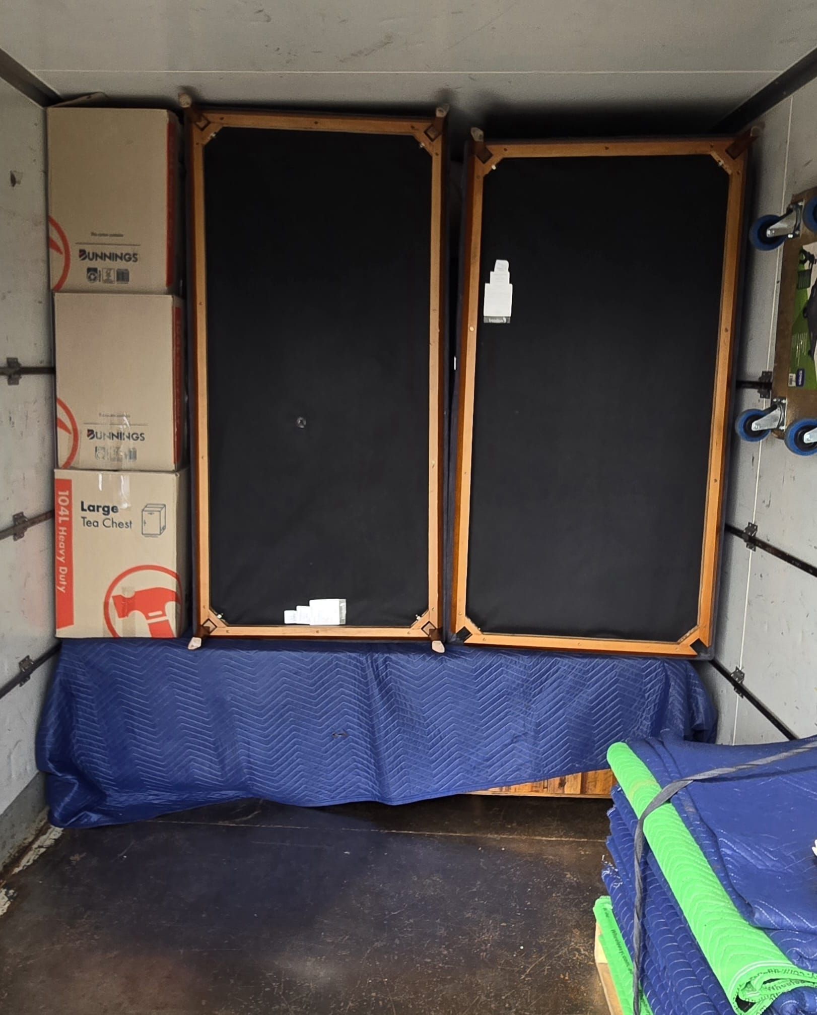 Van interior with covered window panels, blue tarp along the bottom, and a green chair in the foreground