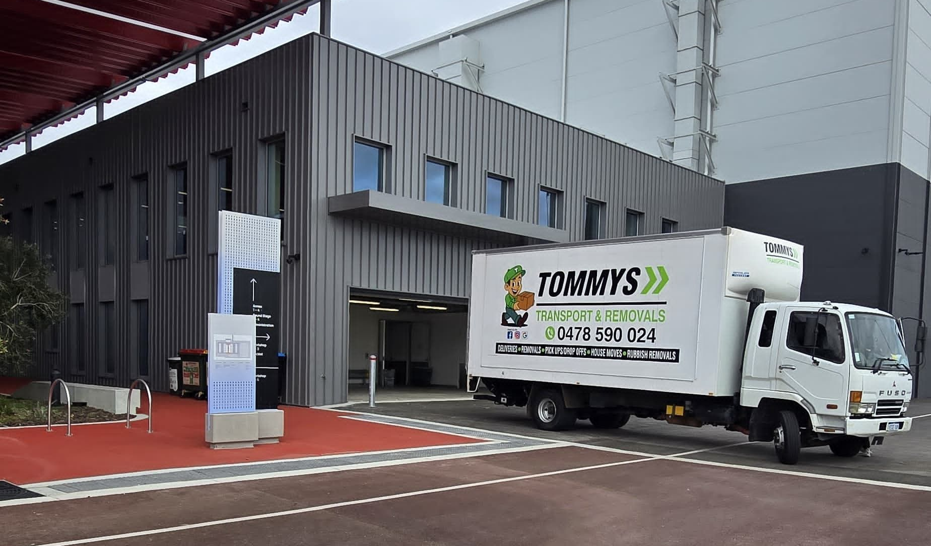 Tommy's removalist truck parked outside a modern gray building.