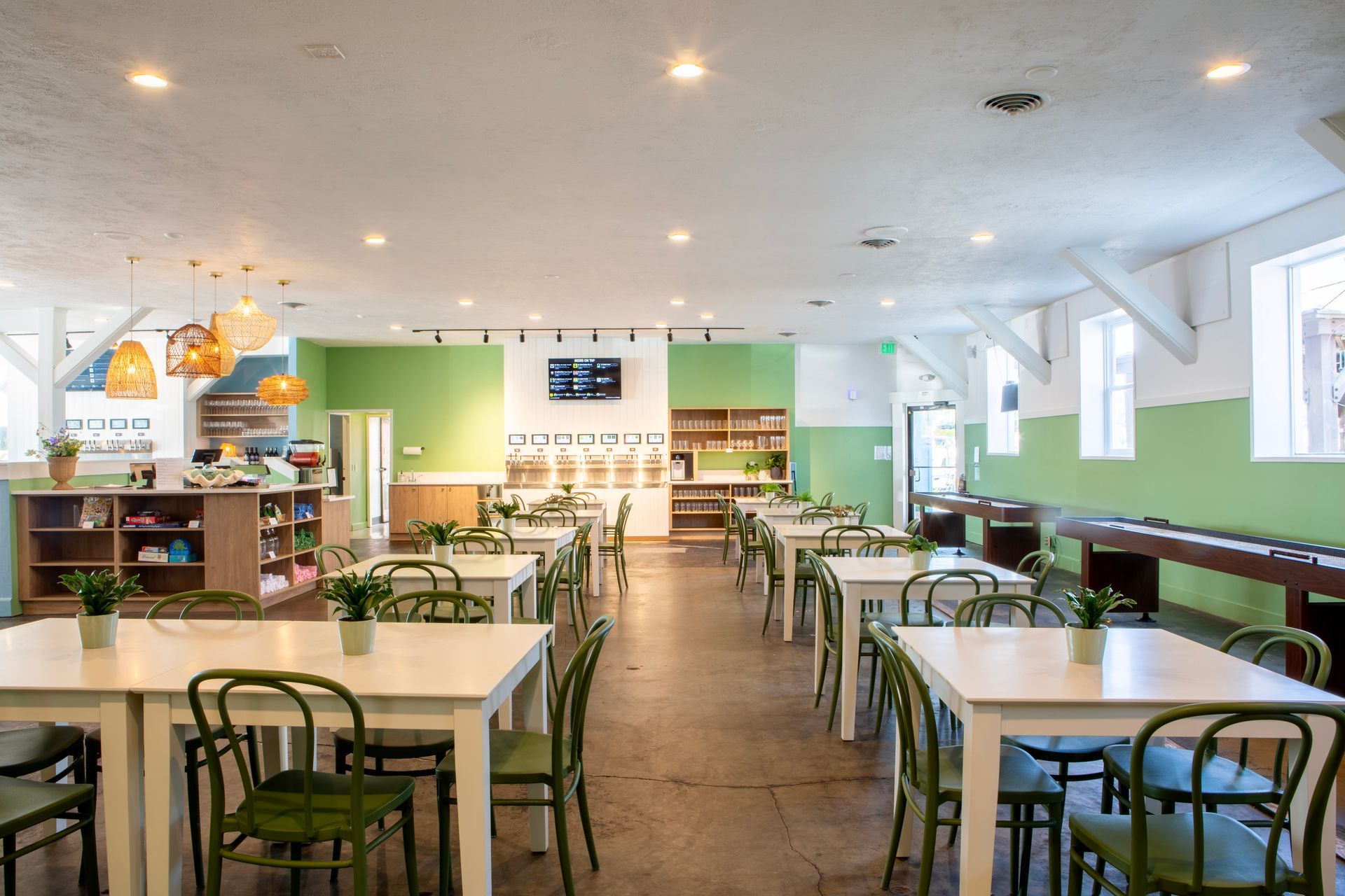 Empty restaurant interior with white tables, green chairs, and light green accent walls.