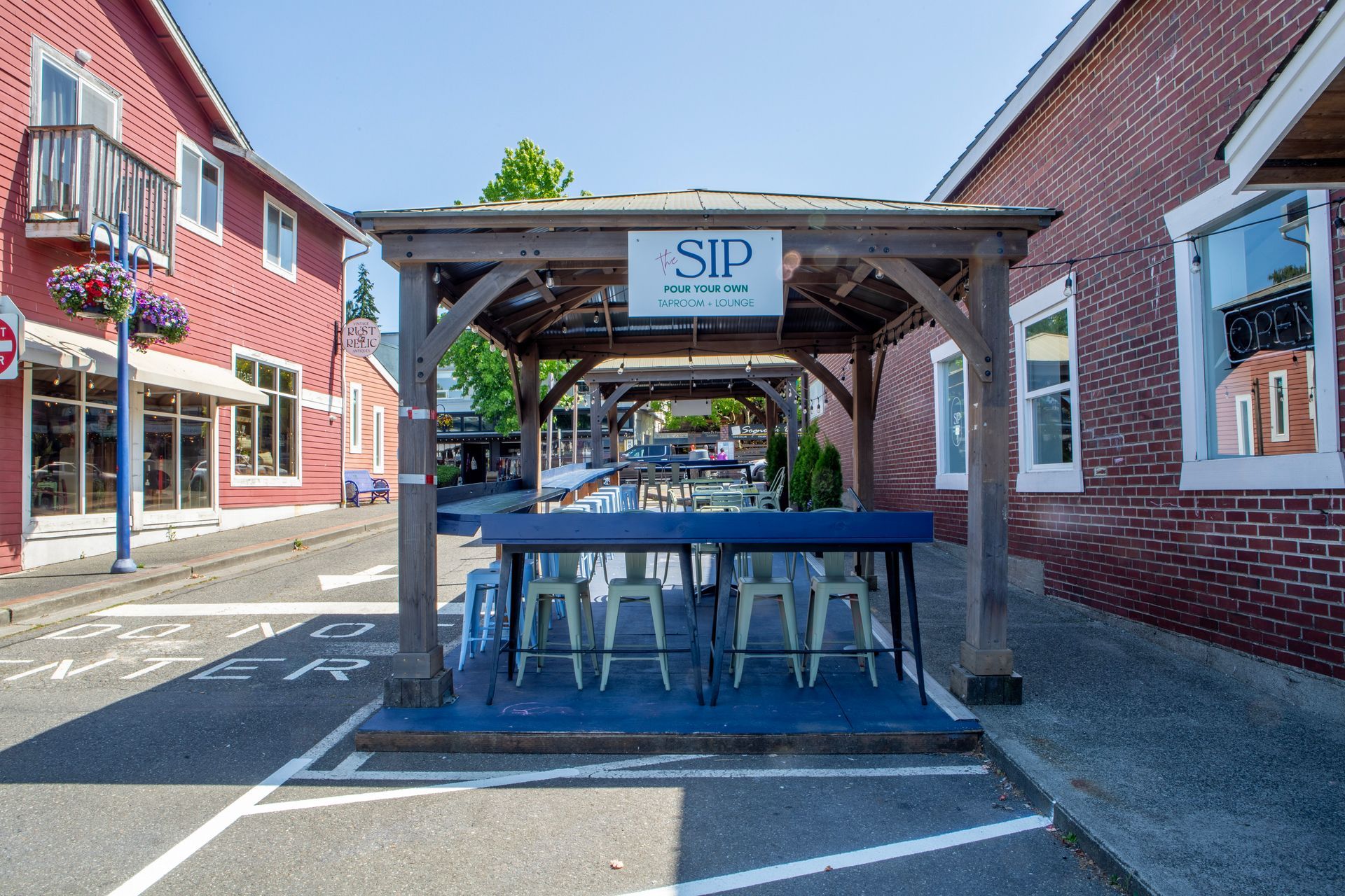 Wooden gazebo with bar seating outside SIP restaurant between two brick buildings.