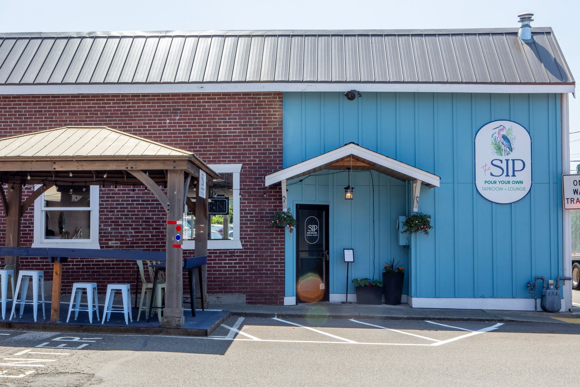 Exterior of SIP Coffee Co., a brick and blue building, with a wooden patio area.
