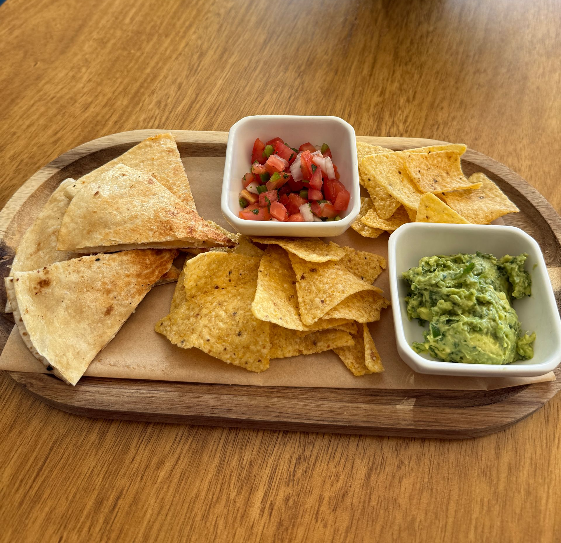 Chips, breadsticks, dips, and a glass of wine on a wooden table.