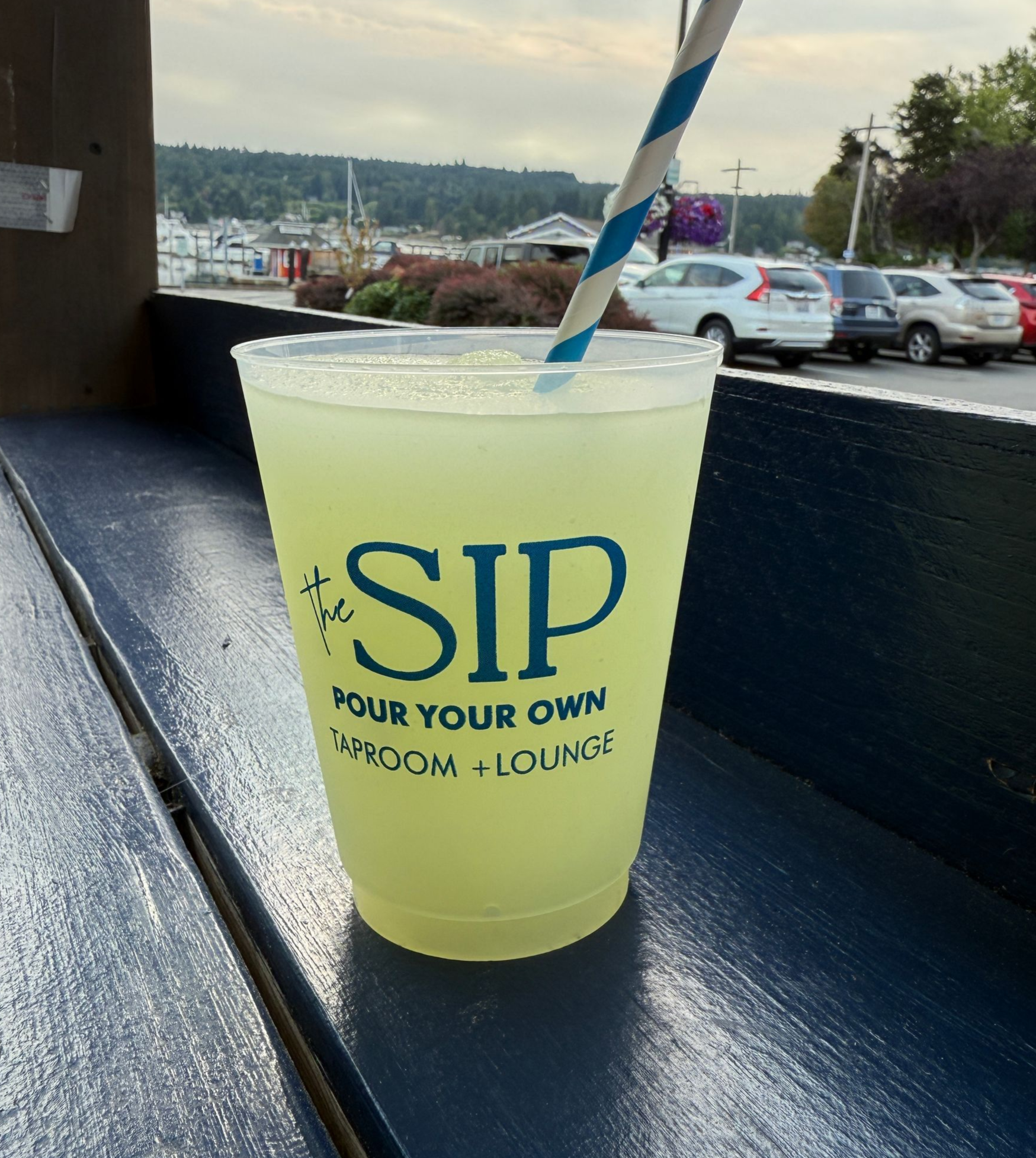 A refreshing lemonade slushie in a plastic cup with a striped straw. Outdoors, overlooking downtown Poulsbo marina.
