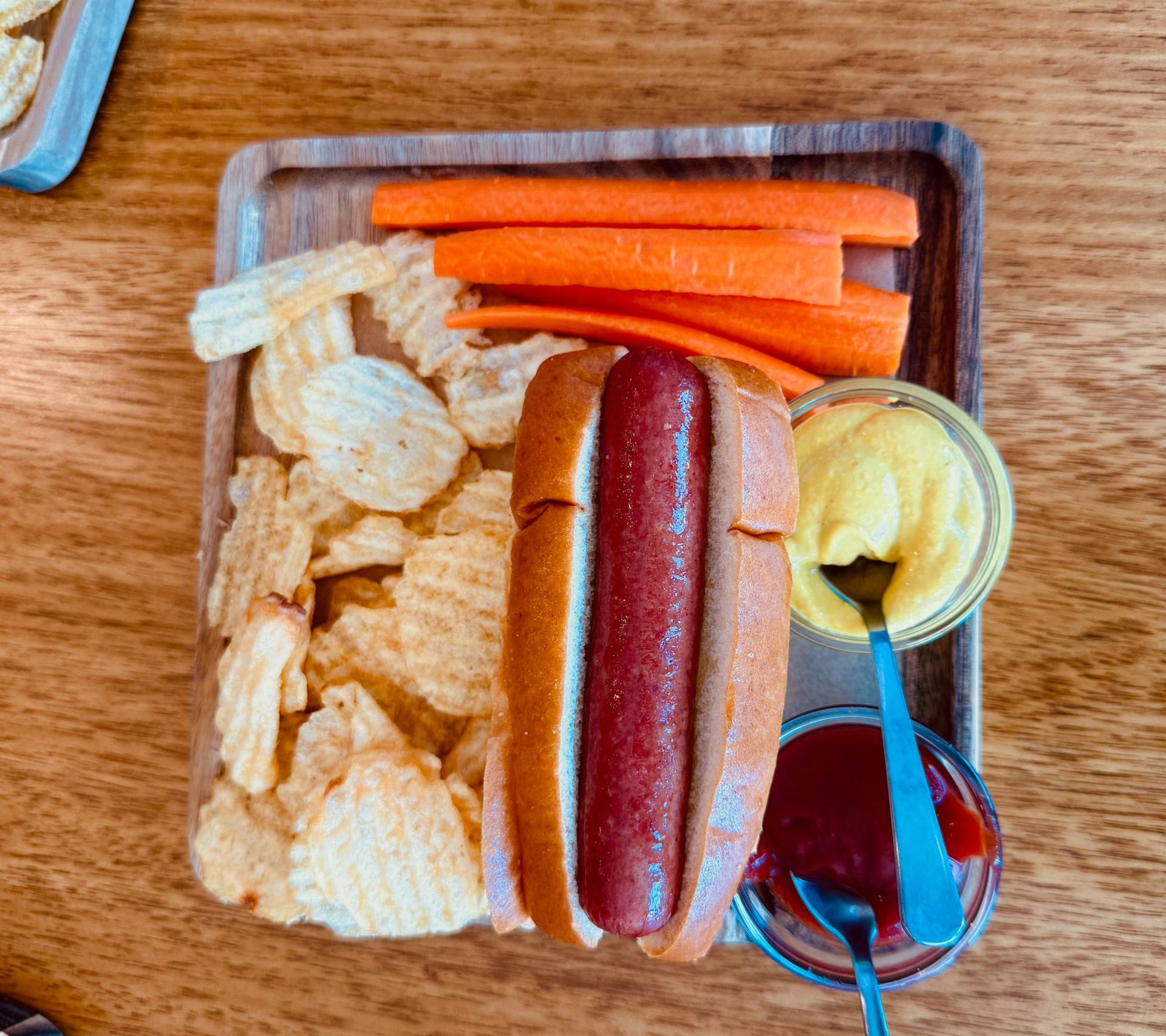 Chips, breadsticks, dips, and a glass of wine on a wooden table.