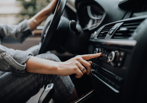 Driver adjusting the car’s climate controls inside a modern vehicle cabin.