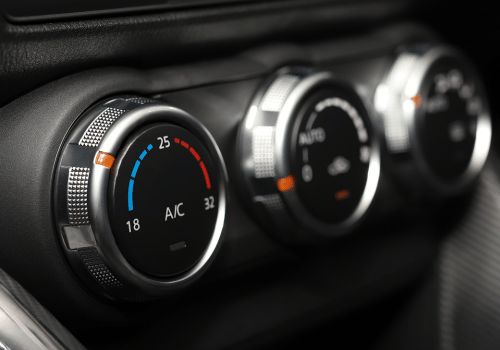 Close-up of car AC temperature controls inside a vehicle dashboard with climate settings displayed.