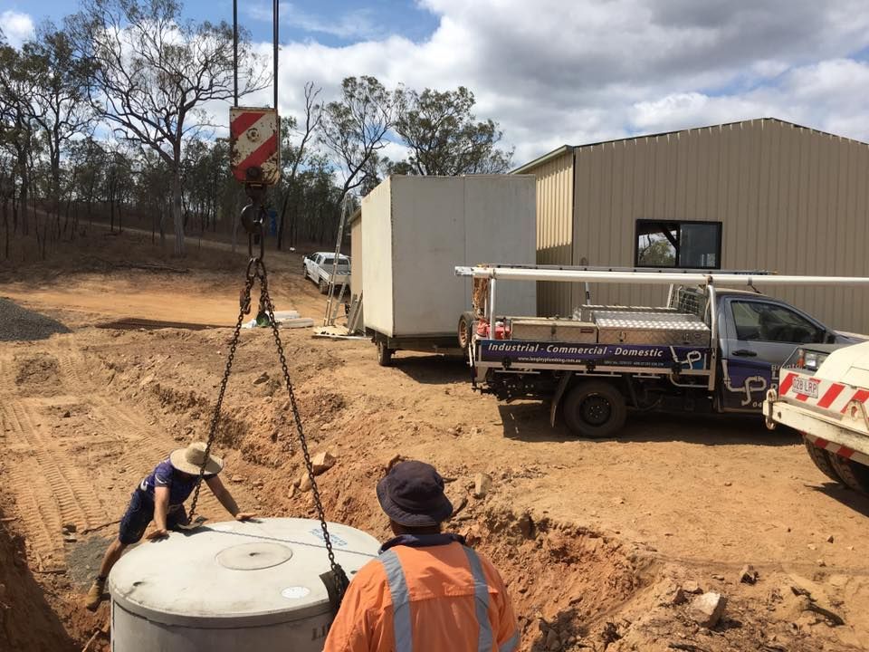 Workers Lowering a Concrete Tank Into a Trench, with a Crane — Langley Plumbing in Mareeba, QLD