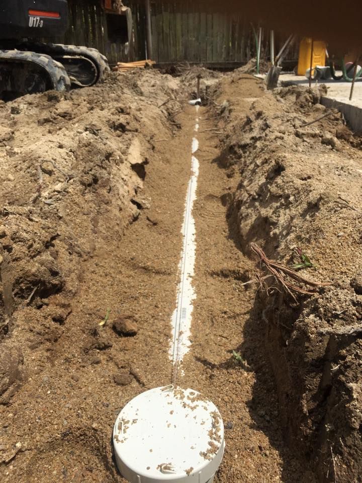 Trench Dug in Dirt With White Pvc Pipes, Likely for Plumbing — Langley Plumbing in Mareeba, QLD