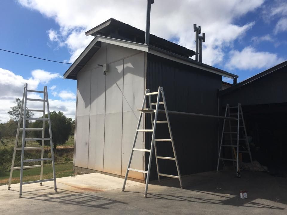 Building With Gray and Black Siding, Multiple Ladders, and Chimneys — Langley Plumbing in Mareeba, QLD