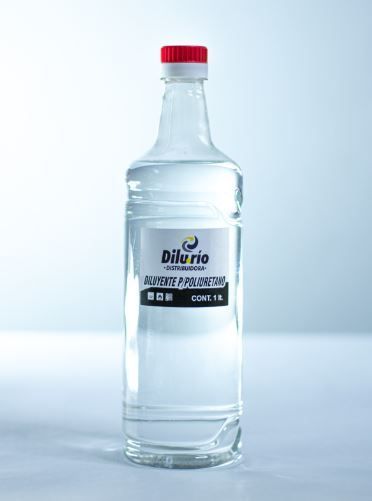Botella transparente de líquido con tapón rojo y etiqueta.