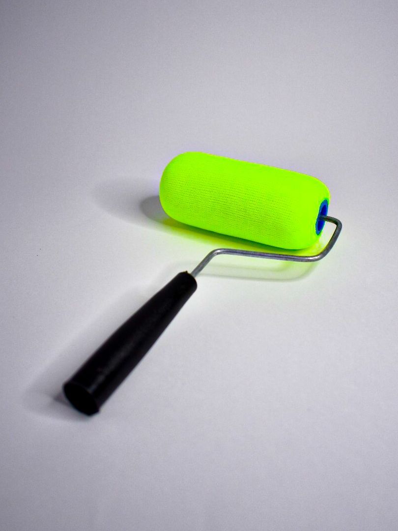 Rodillo de pintura verde con mango negro.