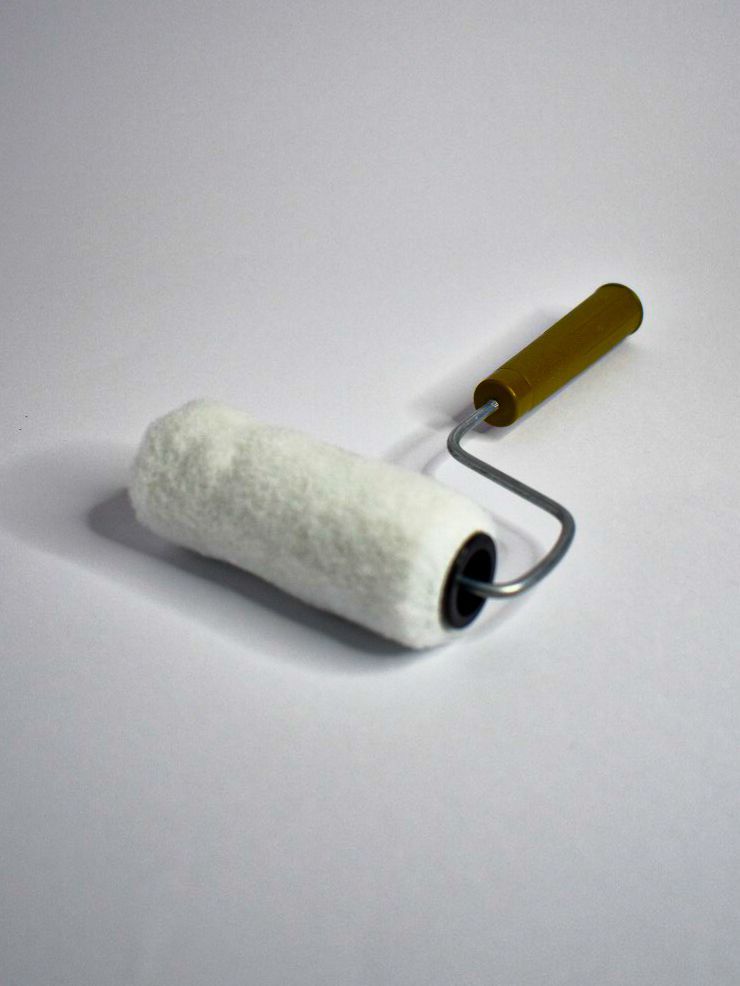 Rodillo para pintar con funda mullida de color blanco y mango de madera.
