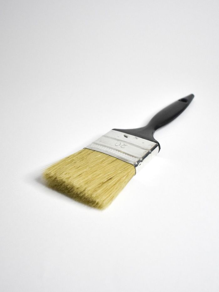 Pincel con mango negro, en ángulo sobre fondo blanco.